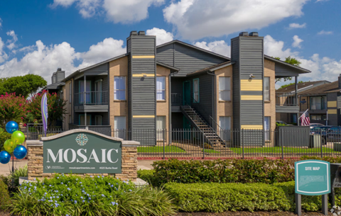 The image shows a building with the name MOSAIC on a sign in front of it.