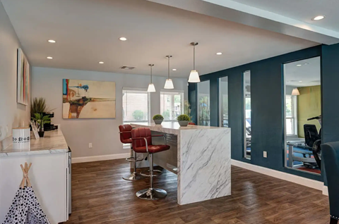 A modern kitchen with a white island and red chairs.