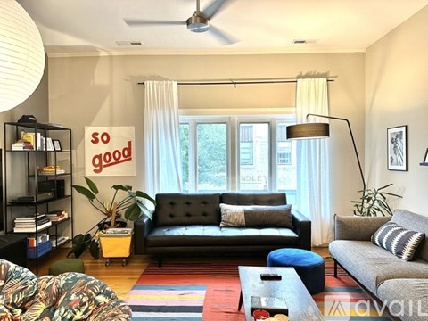 A living room with a black couch and a sign that says "so good".