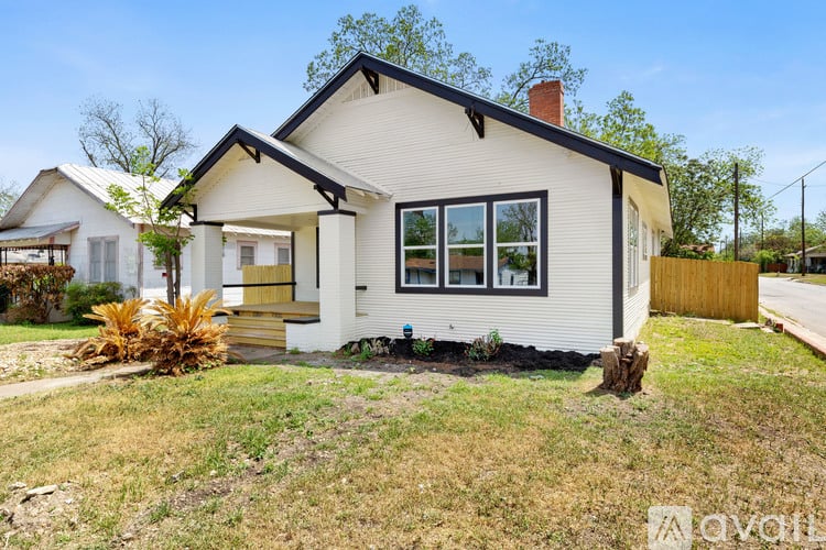 A white house with a black roof and a brown door is for sale.