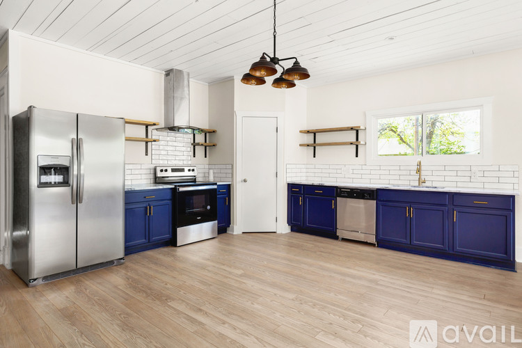 A kitchen with blue cabinets and a stainless steel refrigerator.