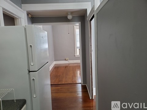 A white refrigerator is in a kitchen with wood floors.