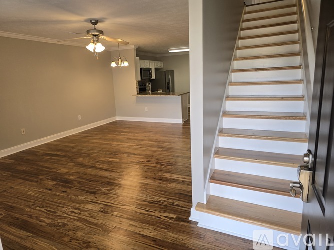 A room with wooden floors and a staircase leading to another room.