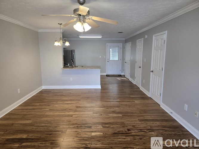 A spacious room with wood flooring and a ceiling fan.