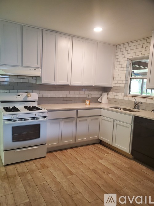 A kitchen with white cabinets and a wooden floor.
