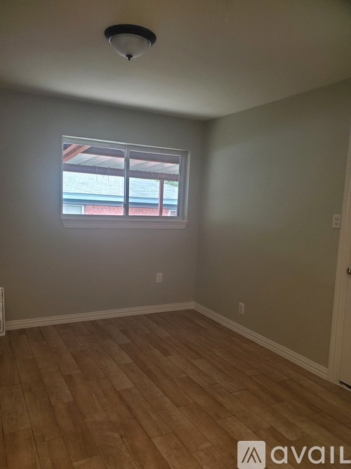A room with wooden flooring and a window.