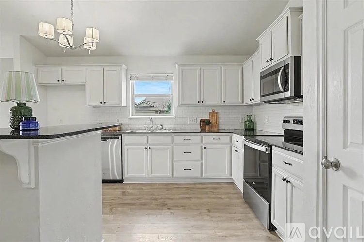 A kitchen with white cabinets and black countertops.