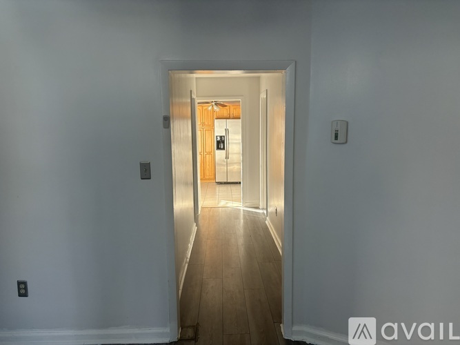 A hallway with a wooden floor and a door at the end.