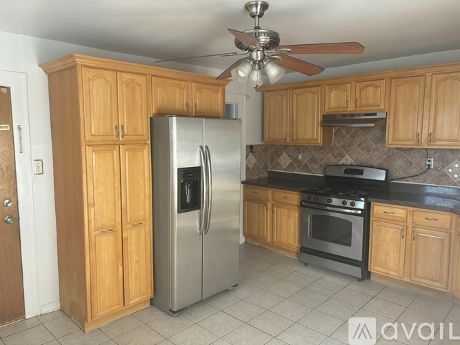 A kitchen with wooden cabinets and a stainless steel refrigerator.