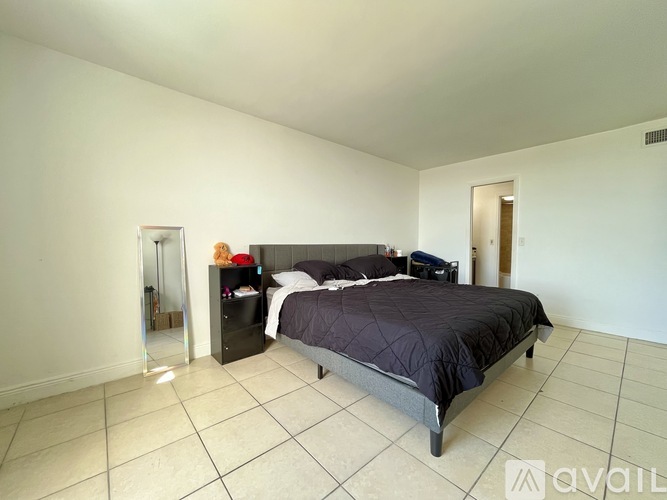 A bedroom with a bed, nightstand, and a dresser with a mirror.