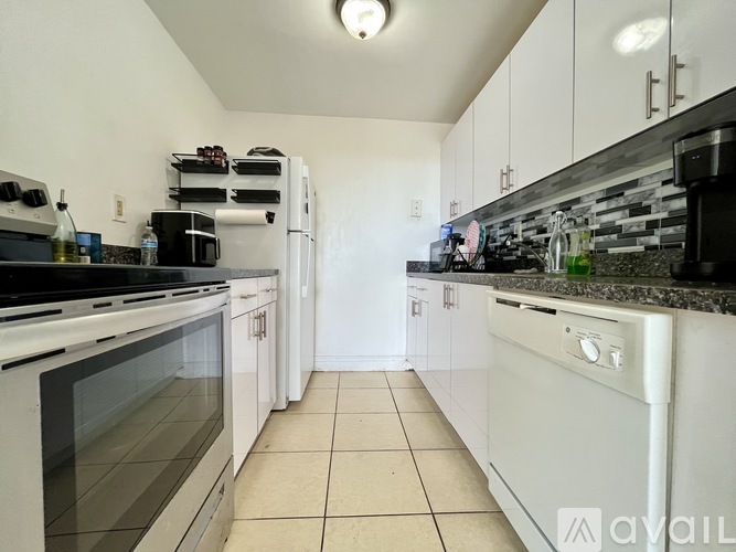 A kitchen with white cabinets and a black countertop.