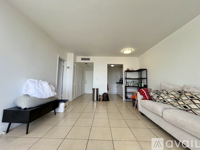 A sparsely furnished living room with a white couch and a black bench.