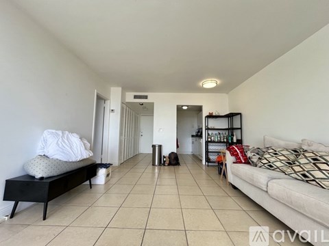 A sparsely furnished living room with a white couch and a black bench.
