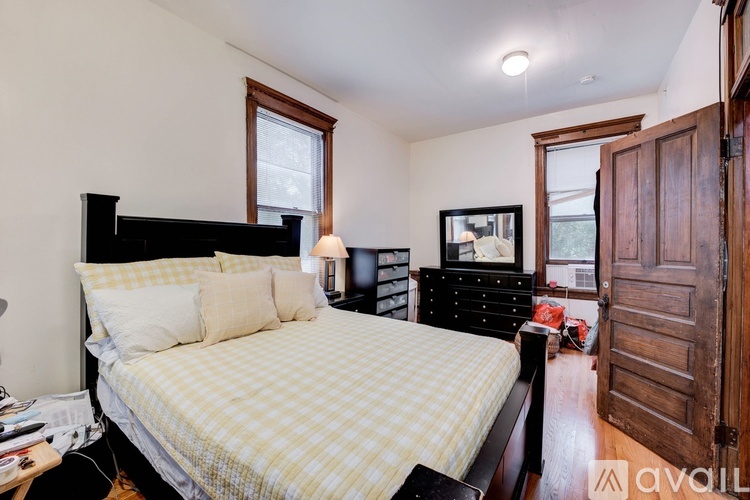 A bedroom with a bed, dresser, and a window.