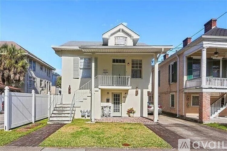 A white two-story house with a balcony on the second floor.