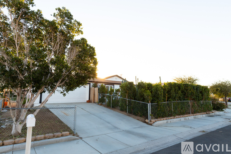 A house with a fence and a tree in front of it.