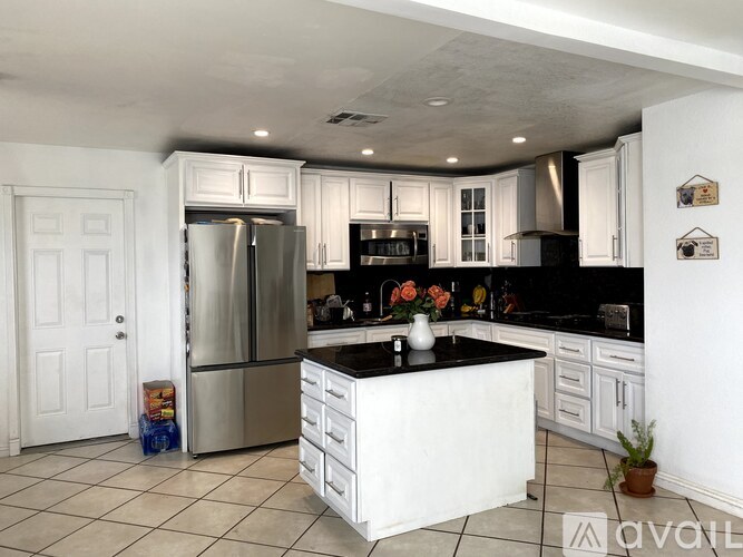 A kitchen with white cabinets and a black countertop.