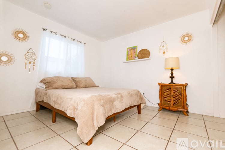 A bedroom with a bed, a lamp, and wall decorations.