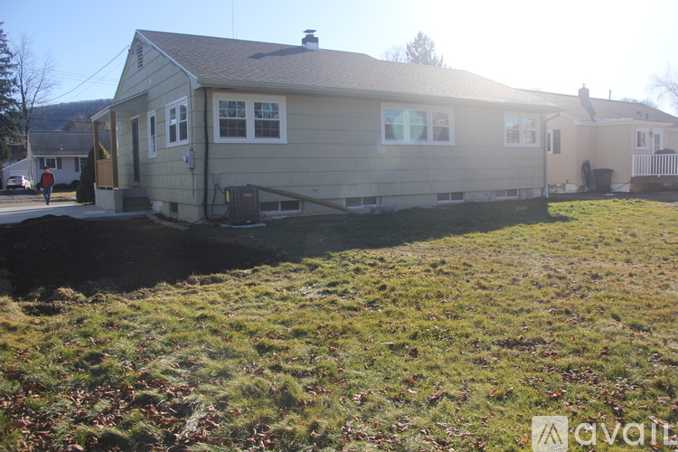 A house with a brown roof and a grey siding is surrounded by a grassy area.