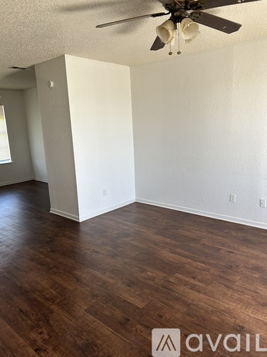 A room with a ceiling fan and wooden flooring.