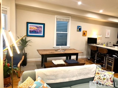 A living room with a couch, a table, and a painting on the wall.
