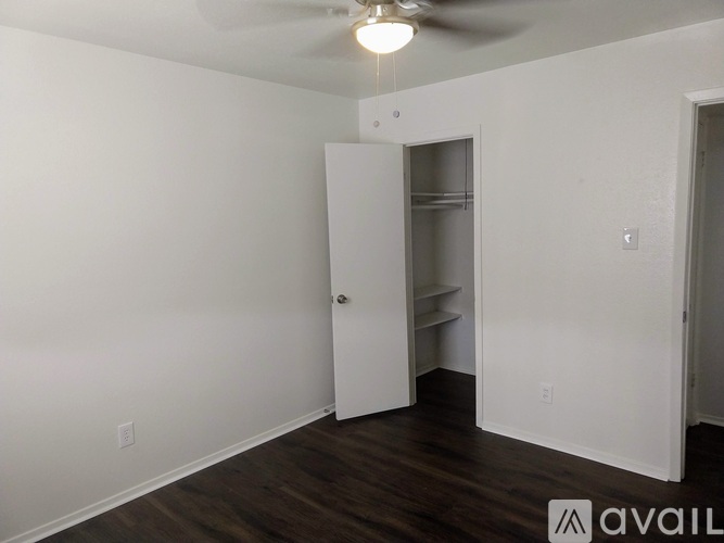 A room with a ceiling fan and a door leading to another room.