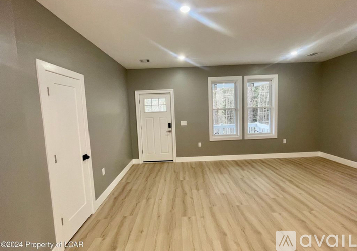 A room with wooden flooring and two doors, one of which is open.