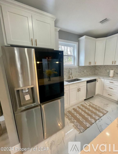 A kitchen with a stainless steel refrigerator and white cabinets.
