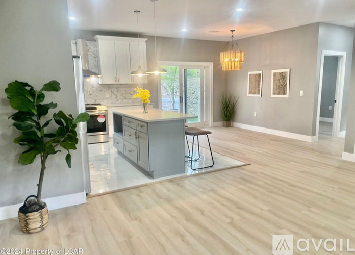 A modern kitchen with a wooden floor and white walls.