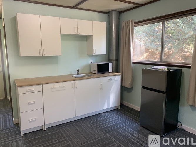 A kitchen with white cabinets and a black refrigerator.