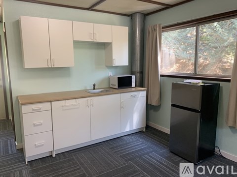 A kitchen with white cabinets and a black refrigerator.