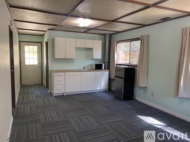 A room with a carpeted floor and a window with curtains.