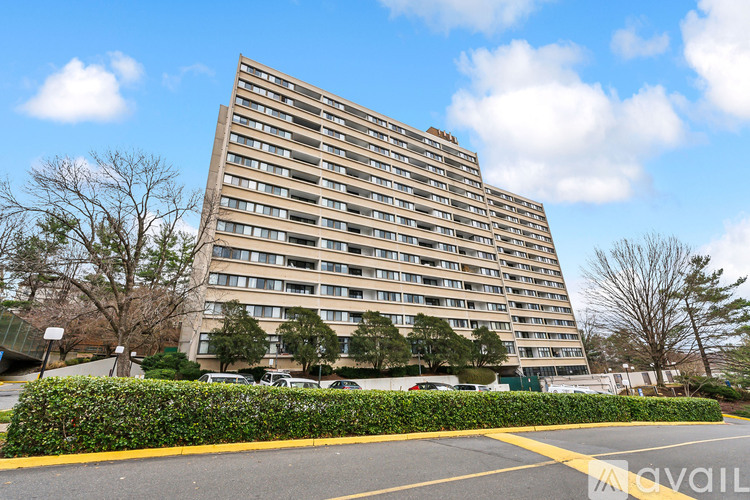 A tall residential building with a parking lot in front.