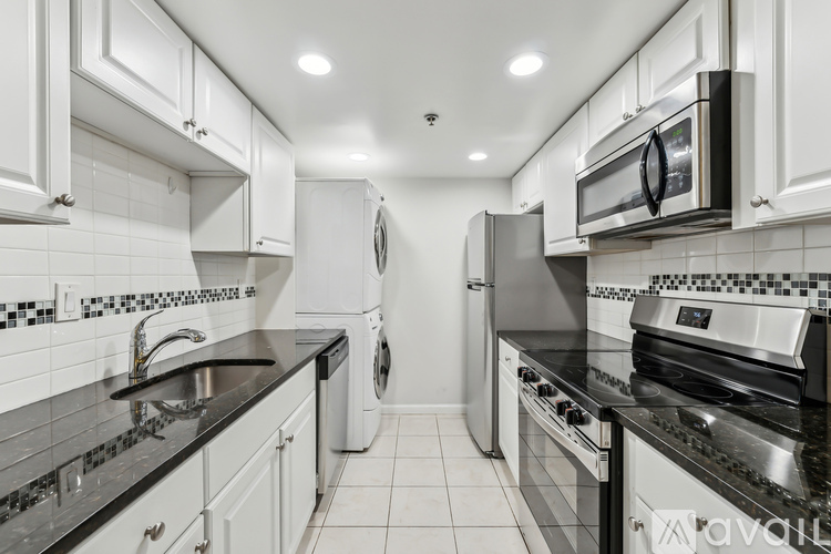 A modern kitchen with white cabinets and black countertops.