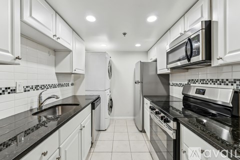 A modern kitchen with white cabinets and black countertops.