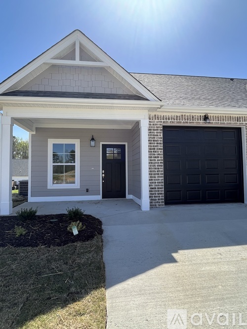 A house with a black garage door and a grey roof.