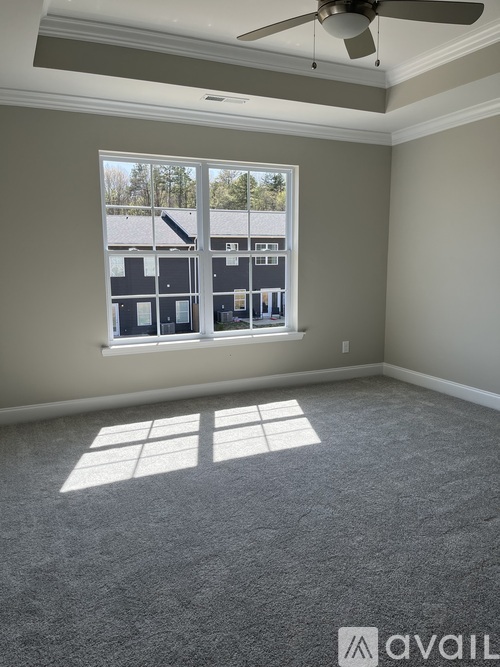 A room with a carpeted floor and a window showing a view of a building.