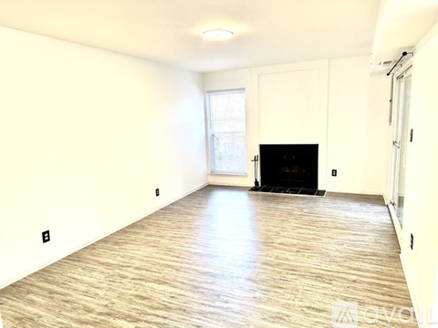 A spacious living room with a fireplace and a window.