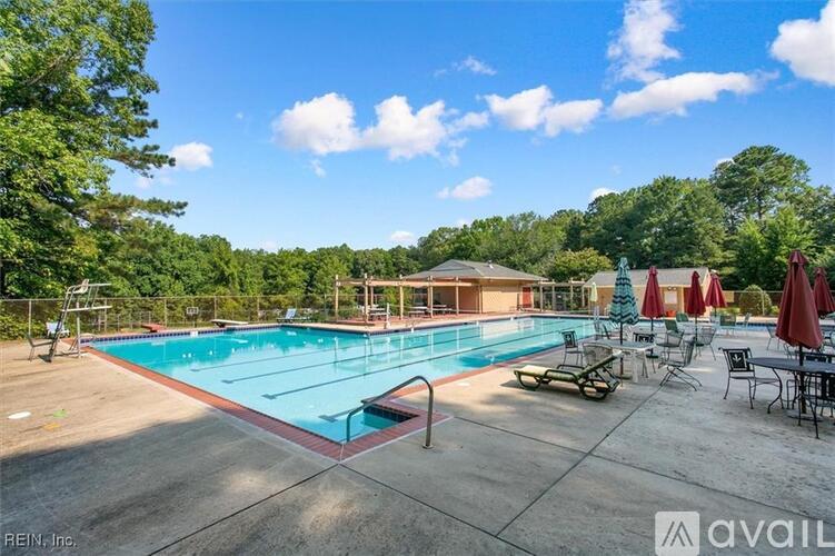 A large outdoor swimming pool surrounded by trees and lounge chairs.