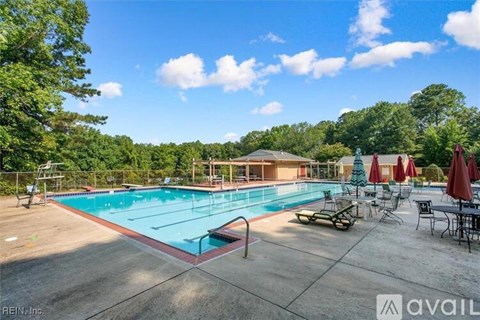 A large outdoor swimming pool surrounded by trees and lounge chairs.