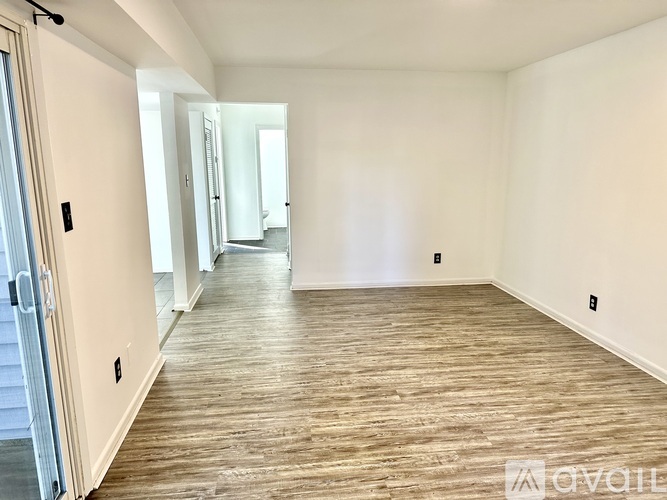 A spacious room with wooden flooring and white walls.