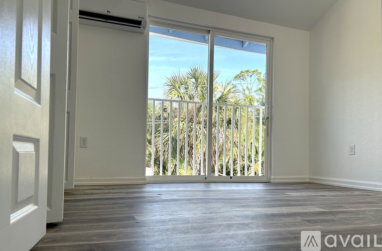 A room with a sliding door leading to a balcony with trees.