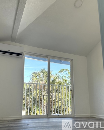 A room with a sliding door leading to a balcony with a railing.