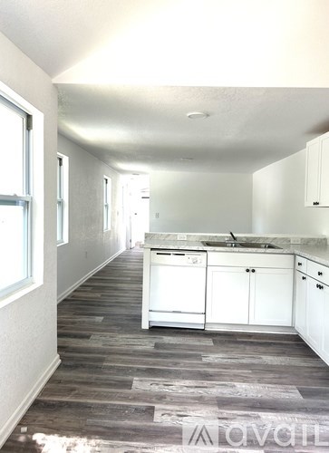 A kitchen with white cabinets and a wooden floor.