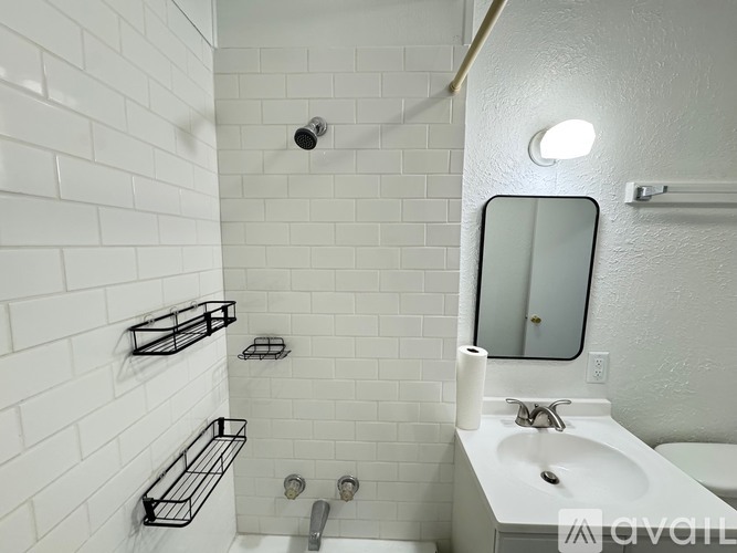 A white bathroom with a sink, mirror, and shower.