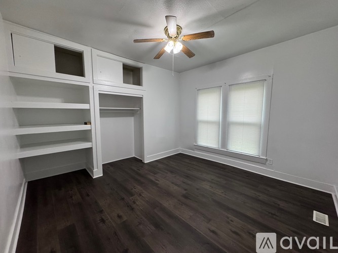 A room with a ceiling fan and wooden flooring.