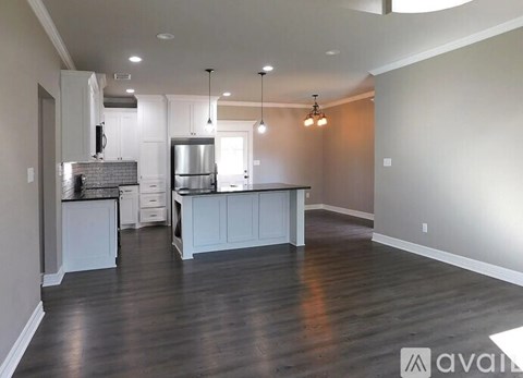 A kitchen with white cabinets and a wooden floor.
