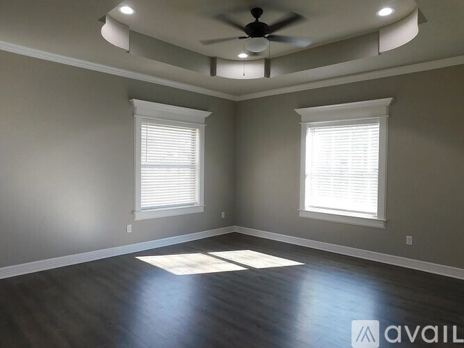 A room with a ceiling fan and two windows.