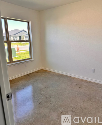 A room with a window and a view of a house across the street.