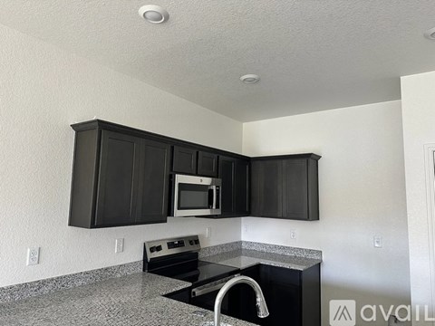 A kitchen with black cabinets and a granite countertop.